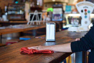 Female server waitress hand wiping cleaning restaurant table - obrazy, fototapety, plakaty