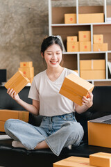 Portrait of a small business startup, SME owner, female entrepreneur, working, unboxing, checking orders online. To prepare to pack boxes for sale to SME customers online business ideas