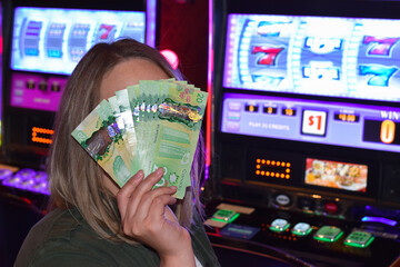 Woman covering her face with canadian cash money winnings in casino