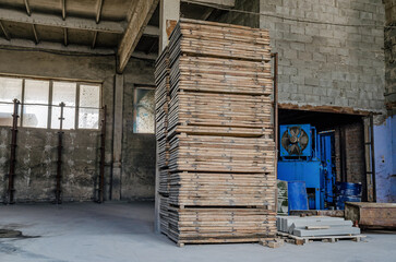 Wooden pallets in a warehouse. Empty warehouse. Brick walls, windows in the walls. Interior of a warehouse, factory.