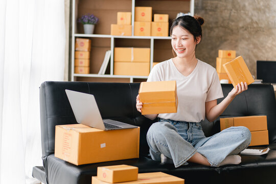 Portrait of a small business startup, SME owner, female entrepreneur, working, unboxing, checking orders online. To prepare to pack boxes for sale to SME customers online business ideas