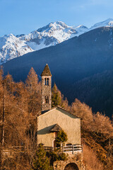 The church of San Clemente, in the mountains of Val Camonica with the setting sun, near the town of Vezza d'Oglio, Italy - January 2022.