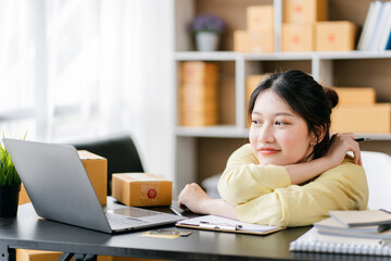 Portrait of a small business startup, SME owner, female entrepreneur, working, unboxing, checking orders online. To prepare to pack boxes for sale to SME customers online business ideas