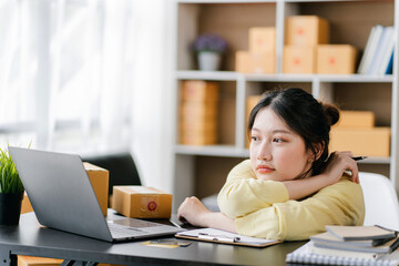 Portrait of a small business startup, SME owner, female entrepreneur, working, unboxing, checking orders online. To prepare to pack boxes for sale to SME customers online business ideas