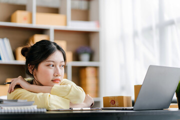 Portrait of a small business startup, SME owner, female entrepreneur, working, unboxing, checking orders online. To prepare to pack boxes for sale to SME customers online business ideas