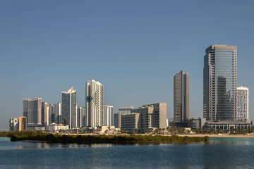 Fototapeta na wymiar Modern high-rise residential and office buildings on Al Reem island and sea water with mangrove trees in Abu Dhabi, UAE
