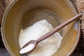 Large Bowl Containing a Little Flour and a Long Wooden Spoon and Wheat Outside