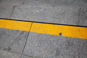 Fototapeta premium Yellow stripe on step of stone staircase