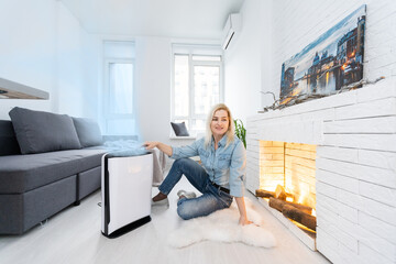 woman turning on and using the modern air purifier in the living room, air purifier is a popular appliance - household electricity. Air purifier can help to purify the air.
