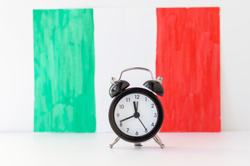 Alarm clock and abstract hand drawn Italian flag on background. Parliament elections, Liberation...