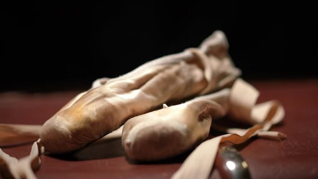Close-up pointies lying on red floor at black background. Ballet shoes with no people closeup. Art and choreography concept