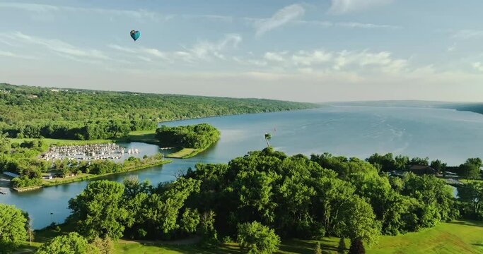 Ithaca NY USA June 26, 2022: Video of a beautiful hot air balloon, near Ithaca NY, traveling over the  Cayuga Inlet and Cayuga Lake on a sunny Sunday morning