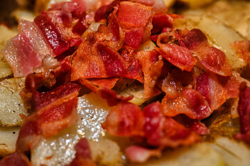 Bacon and potatoes frying on a stove top.