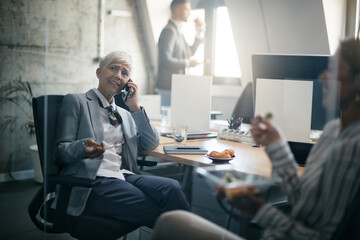 Mature businesswoman talking on the phone while working at corporate office.