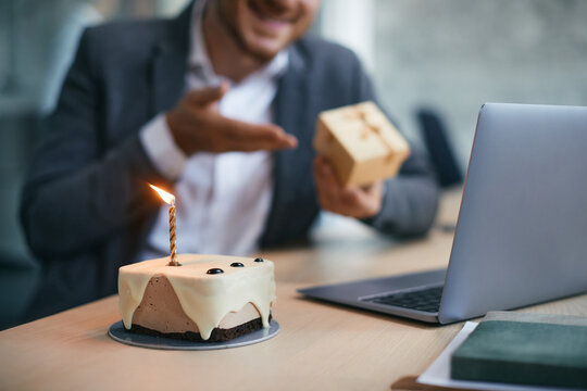Close up of Birthday cake with businessman making video call in background.