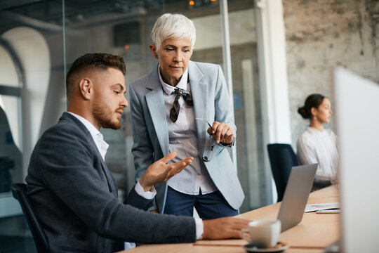 Business Colleagues Collaborate While Working On Laptop In Office.