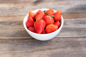 fresh strawberries in a bowl on wooden table