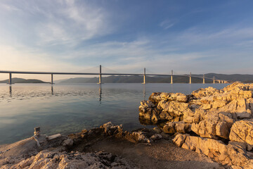 Bridge over the sea to the island of Peljesac in Croatia. Calm sea level with a beautiful white bridge in the foreground white stones.