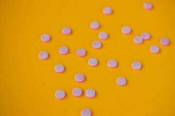 Fototapeta na wymiar Pink pills on yellow background