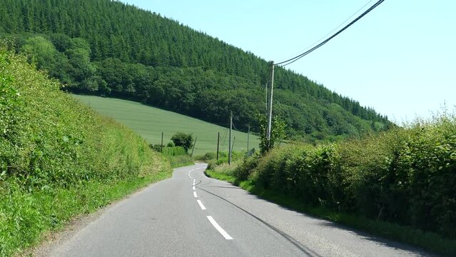 Car windscreen view driving downhill road A44 in South Wales UK in summer.