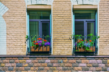 Fototapeta na wymiar Two windows in a brick house with flower boxes
