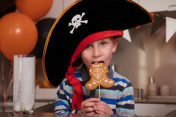 A boy dressed as a pirate eats gingerbread as a Halloween skeleton, drinks milk