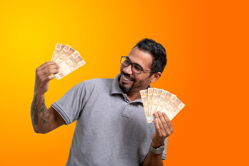 man holding money in both hands, smiling enthusiastically, Brazilian money, orange and yellow...