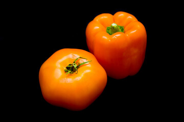yellow pepper and yellow tomato lie on a black background