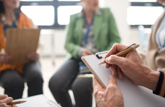 Elderly People Attending Group Therapy Session At Nursing House, Sitting In Circle, Having Conversation With Psychologist, Close-up