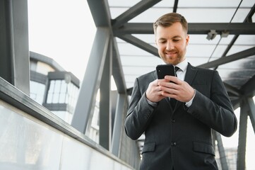 Confident young businessman using cell phone in the city.