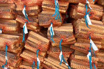 Firewood in the grid. Big pile of firewood packed in nets for sale