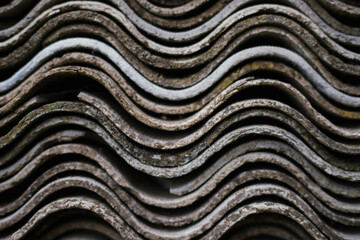 Stacked slate sheets on top of each other. Corrugated asbestos cement sheets.The texture of wavy slate. Building materials. Background.