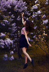 Fantasy girl in levitation. In a fairytale forest on alley with flowers