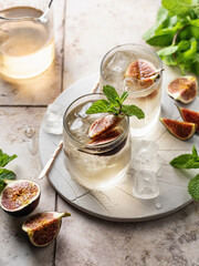 Fig iced cocktail with mint on tile background. Infused fig water. Summer drinks