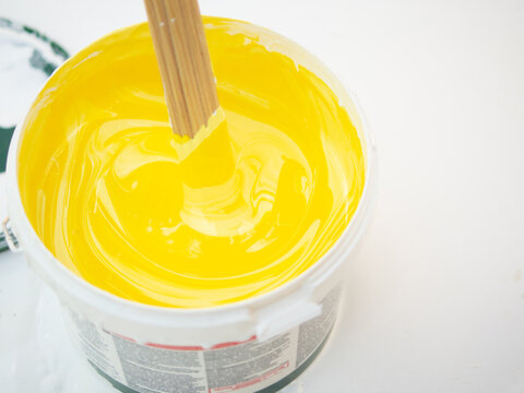 girl painter mixes yellow and white paints, mixes colors with acrylic facade paint. paint mixes in bucket
