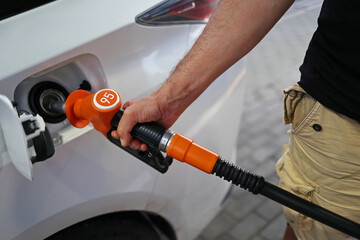 man's hand holds a filling pistol inserted into the gas tank hole of a car at a gas station. Close-up of a hand and a refueling gun. The concept of the high cost of fuel, inside out empty pockets
