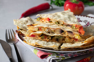 Mexican tortilla quesadilla appetizer with vegetables and cheese in plate on light background
