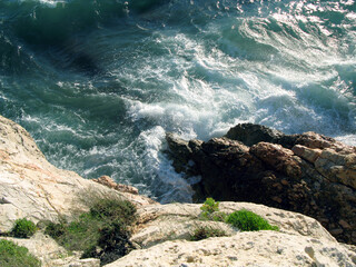Sea wave is removed from rocks and stones, blue water, white foam, bubbles. Mediterranean sea beaches, Salou, spain, summer, vacation