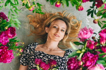 an attractive middle-aged blonde woman lies in flowers on the gray floor.