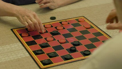 A Caucasian man and woman playing a game of checkers on a old fashion checker board.