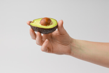 slice of avocado in hand on white background