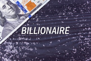 BILLIONAIRE - word (text) on a dark wooden background, money, dollars and snow. Business concept (copy space).