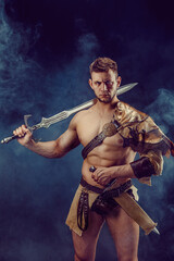 Portrait of handsome muscular gladiator with sword. Isolated. Studio shot. 