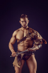 Portrait of handsome muscular gladiator with sword. Isolated. Studio shot. 