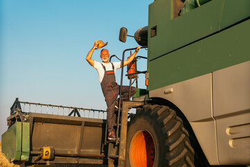 An senior Harvester machine driver climbing into a cab to harvest his wheat field. Farmer getting...