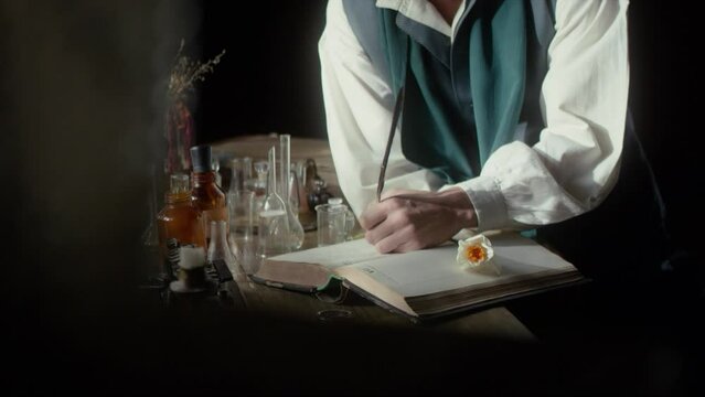 A male perfumer writer with a pen in his hands prepares to write down a recipe for a new fragrance. Medieval style. Cinematic concept. Close-up. 4K video, RED camera