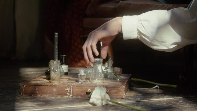 A man's hand plays chess with flasks on a chessboard. The concept of a perfumer, relaxation, creative crisis, reflection, play, invention. Cinematic concept. Close-up. 4K video, RED camera