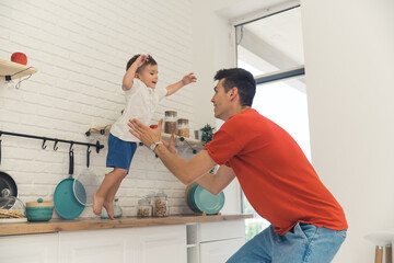 father and his son having fun in the kitchen, a happy family concept. High quality photo