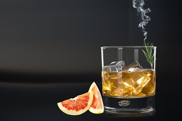 Whiskey or cognac in cristal glass with smoked rosemary, and slice of orange. Alcoholic drink.