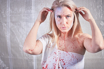 Blonde caucasian Polish woman with blood spray on her face sweeping back her hair. White one...
